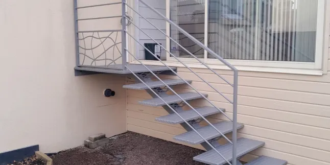 Escalier extérieur 6 marches + 1 palier. Marches en acier larmés. Garde corps en aluminium, cadre 40x20mm, remplissage en lisses D.16 + soubassement habillage décoratif "spline" sur le garde corps droit. 53810 CHANGE