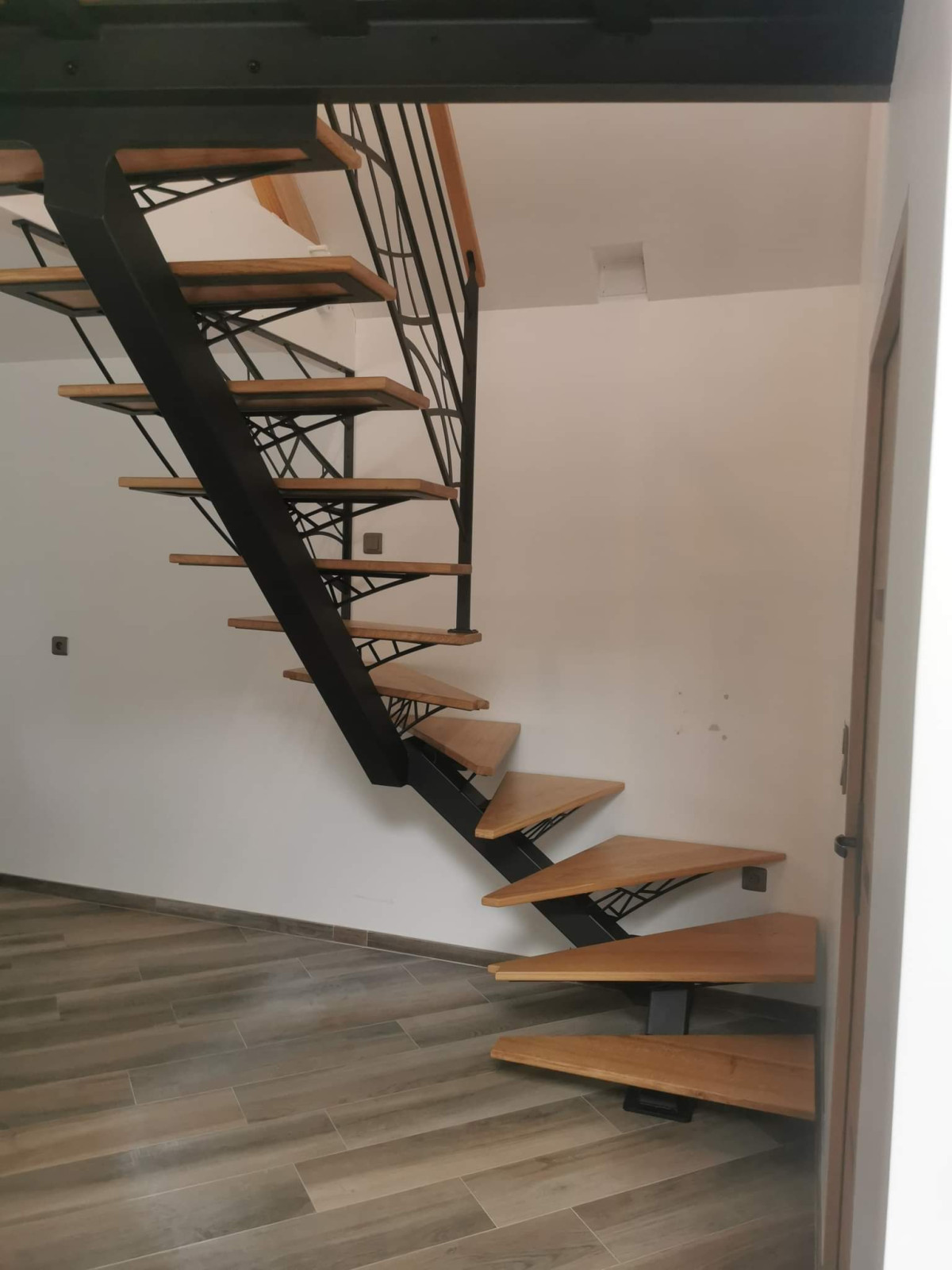 Escalier limon central, 1/4 tournant, sabots n°67, laquage ral noir 2100 sablé, triangulation et garde corps en habillage décoratif courbes, marches et main courante en chêne. 53700 VILLAINES LA JUHEL.