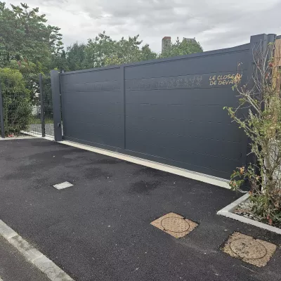 Portail coulissant en aluminium, remplissage en lames avec un habillage décoratif "fleurs" + inscription adresse. Laquage ral 7016 FT 53600 CHATRES LA FORET