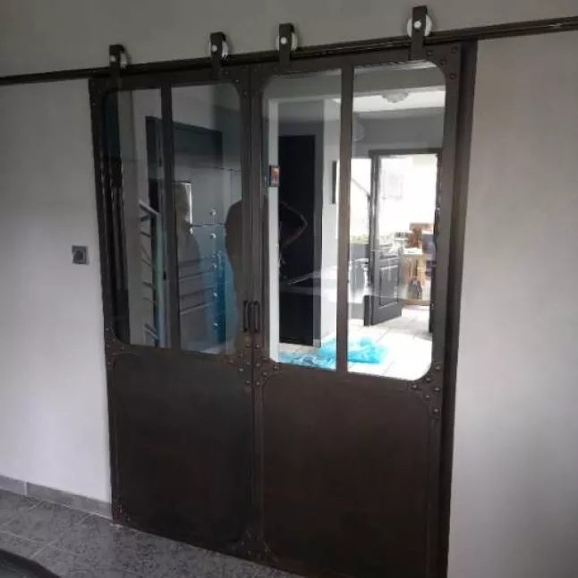 Porte verrière coulissante, châssis en acier 40mm,remplissage en vitrages clair 33/2 feuilleté, soubassement en tôle,roulettes apparentes, finition acier brut rouillé, 53600 EVRON.