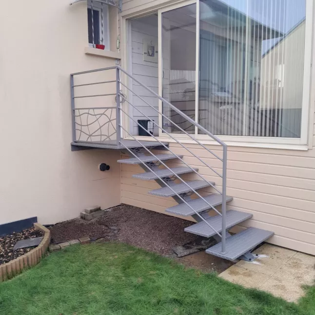 Escalier extérieur 6 marches + 1 palier. Marches en acier larmés. Garde corps en aluminium, cadre 40x20mm, remplissage en lisses D.16 + soubassement habillage décoratif "spline" sur le garde corps droit. 53810 CHANGE